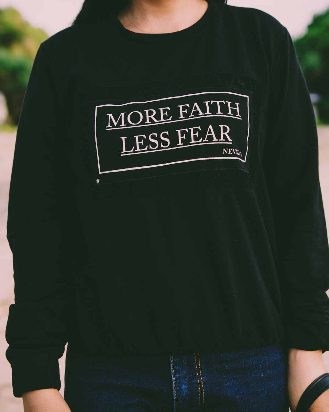 Progetto senza titolo (7) Donna con felpa nera con la scritta “More faith, less fear”